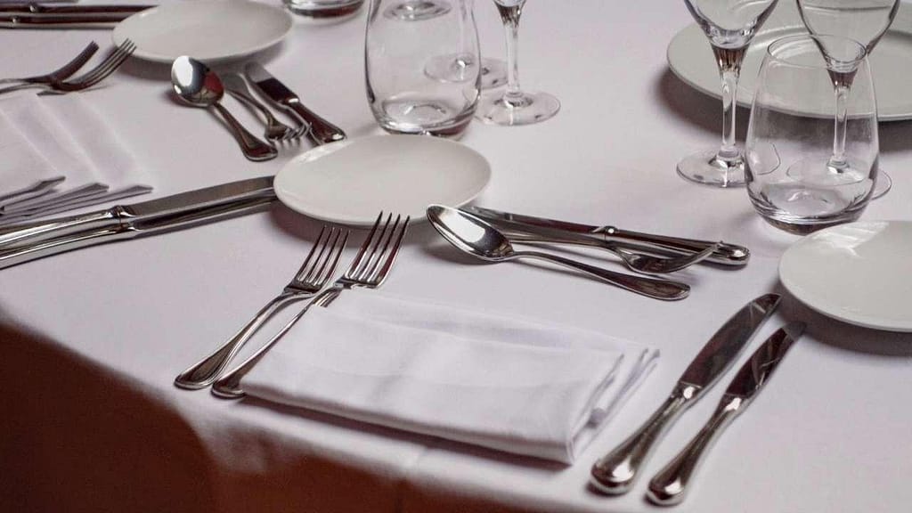 A formal dining table setting featuring elegant silverware, crystal glassware, and porcelain plates illustrating traditional table manners.