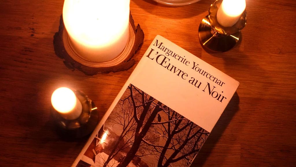 a copy of Marguerite Yourcenar's novel L'oeuvre au noir or The Abyss surounded by candles
